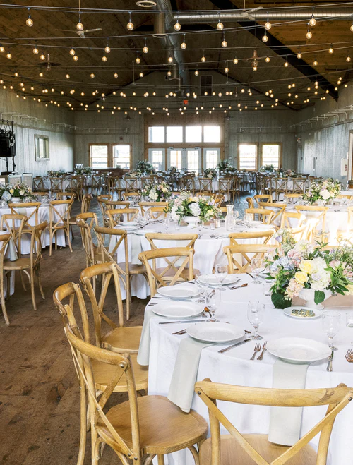 a group of tables in a barn at a wedding RG|NY