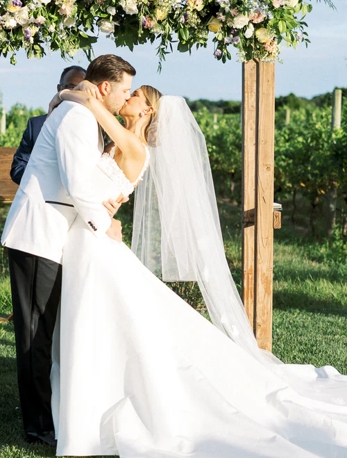 a wedding couple kissing underneath soime flowers RG|NY