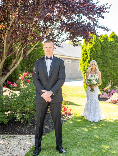 a groom standing with his bride behind him RG|NY